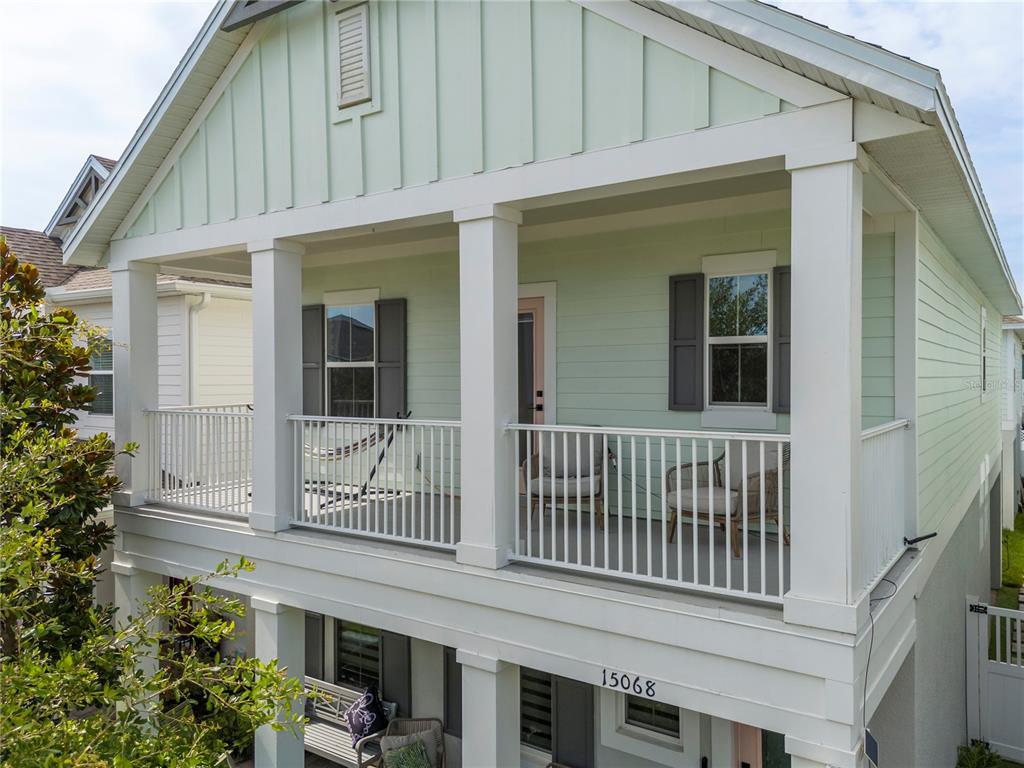 A two-story house features a light green exterior with a covered upper-level balcony and porch — 15068 LEBEAU LOOP, WINTER GARDEN, FL