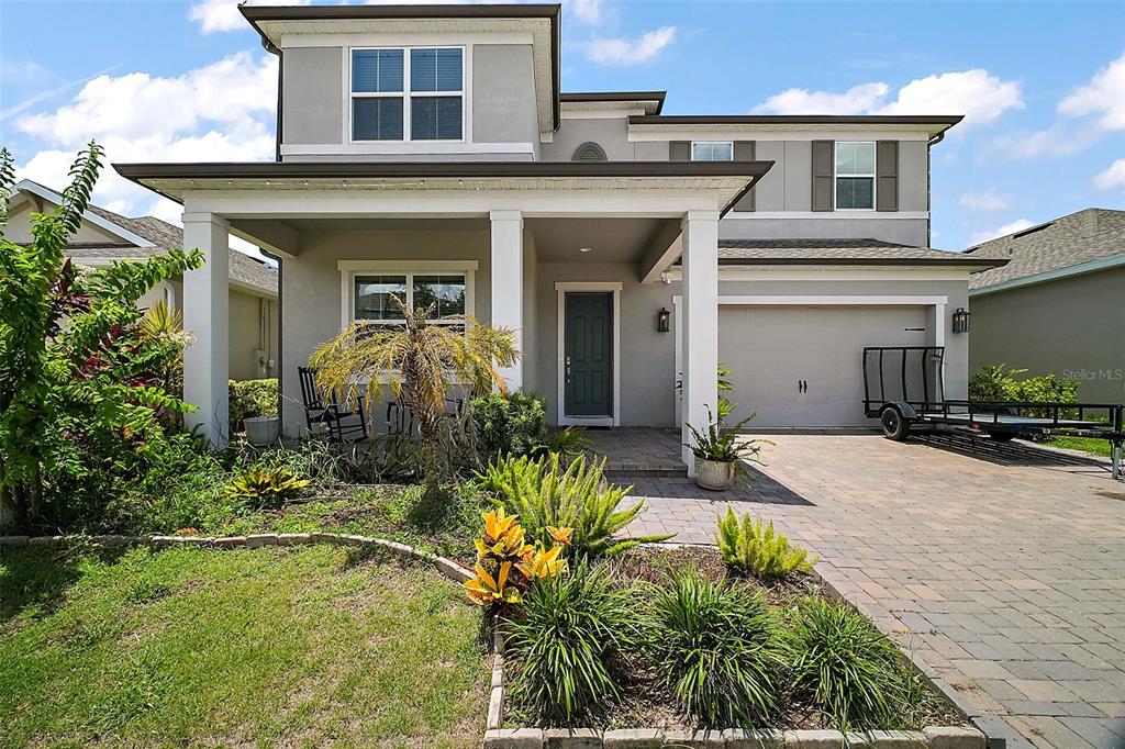 A two-story suburban house with a gray stucco exterior, covered front porch, and paved driveway — 9153 CARMELA AVENUE, DAVENPORT, FL