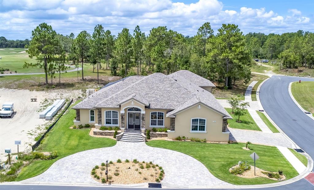 A single-story house with a beige stucco exterior, stone accents, and a paved circular driveway — 17898 SW 72ND STREET ROAD, DUNNELLON, FL