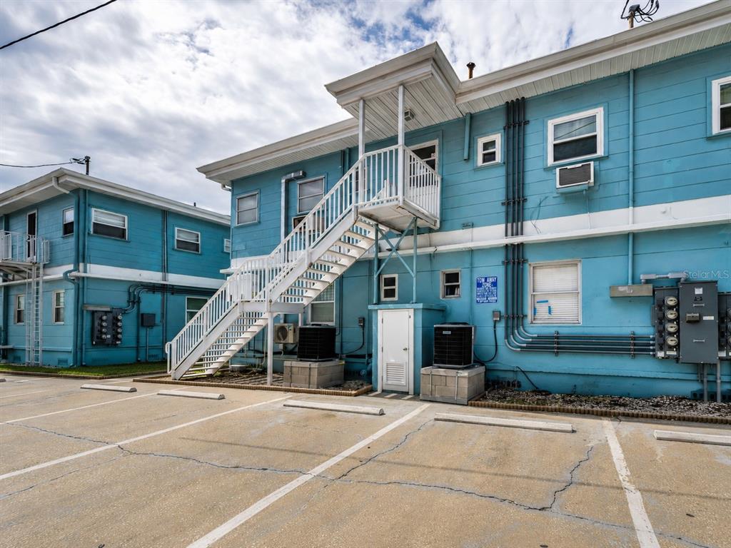 A two-story blue building features an exterior staircase and a paved parking lot in front — 483 E SHORE DRIVE UNIT A4, CLEARWATER BEACH, FL