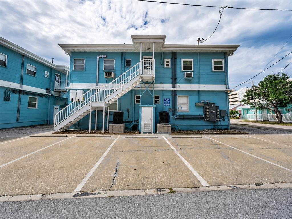 The exterior of a blue building features an outdoor staircase, two wall-mounted water heaters, and parking — 483 E SHORE DRIVE UNIT A4, CLEARWATER BEACH, FL