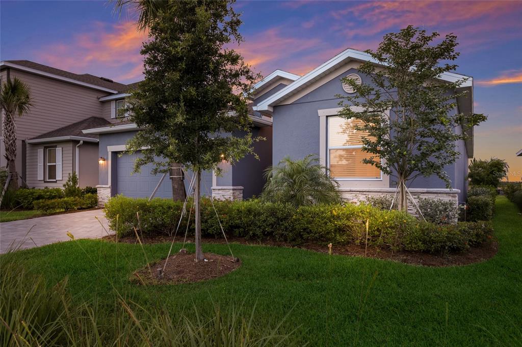 A blue single-story house with a paved driveway and landscaped front yard at sunset — 3535 NIGHT STAR TERRACE, PARRISH, FL