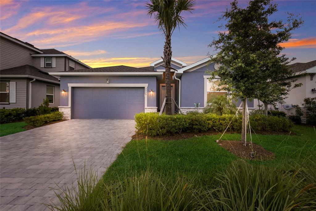 A blue single-story house with a two-car garage and a paved driveway at sunset — 3535 NIGHT STAR TERRACE, PARRISH, FL