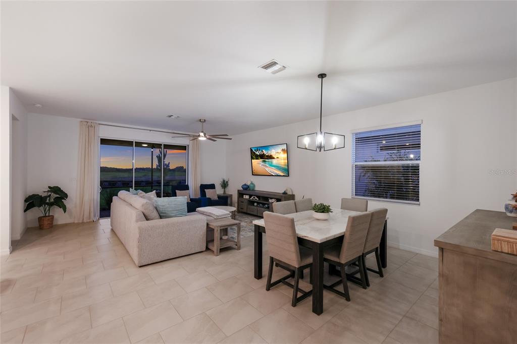 An open-concept living and dining area features tile flooring, a marble-top table, and sliding doors — 3535 NIGHT STAR TERRACE, PARRISH, FL