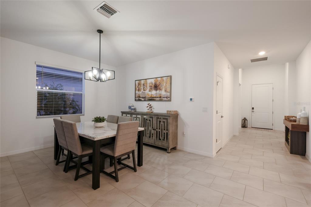 A dining room features a marble-topped table, upholstered chairs, a sideboard, and tile flooring — 3535 NIGHT STAR TERRACE, PARRISH, FL