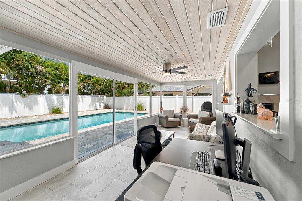 A living room features a white sectional sofa, a glass-topped coffee table, and plantation shutters — 4523 CLEARWATER HARBOR DRIVE S, LARGO, FL