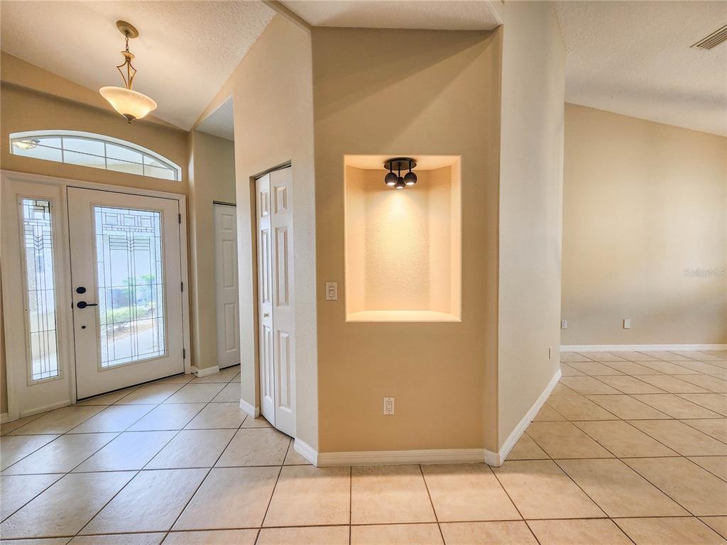 An entryway features a tiled floor, a white front door with glass, and a side window — 44 CROSSTIE COURT, PALM COAST, FL
