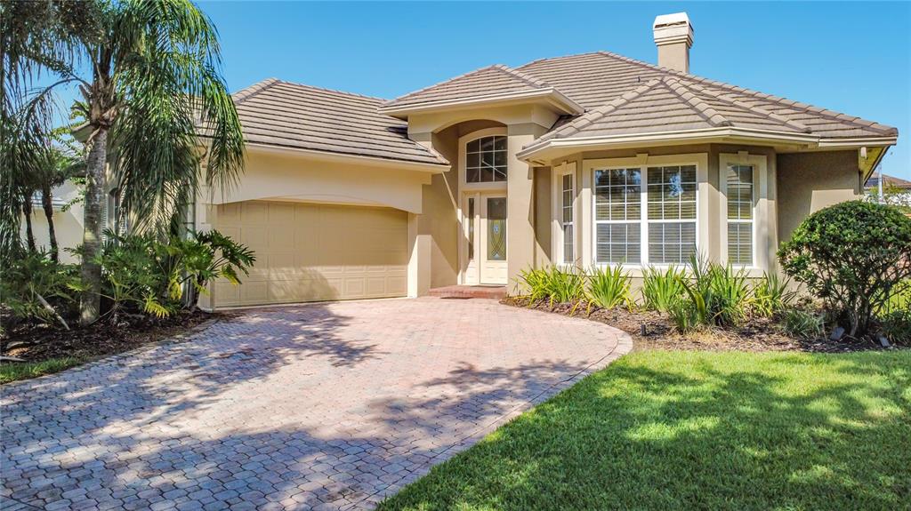 A single-story house with a tan exterior, a tiled roof, and a brick paver driveway — 10824 WOODCHASE CIRCLE, ORLANDO, FL