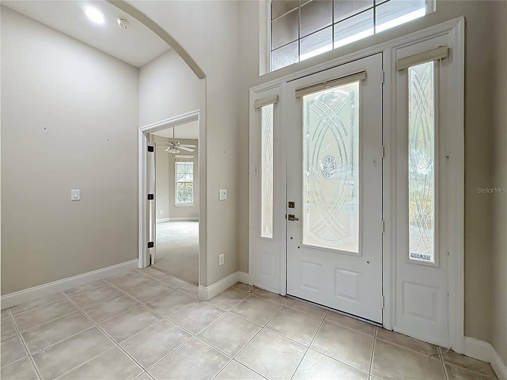 A tiled entryway features a high ceiling, arched doorway, and a white front door with sidelights — 10824 WOODCHASE CIRCLE, ORLANDO, FL