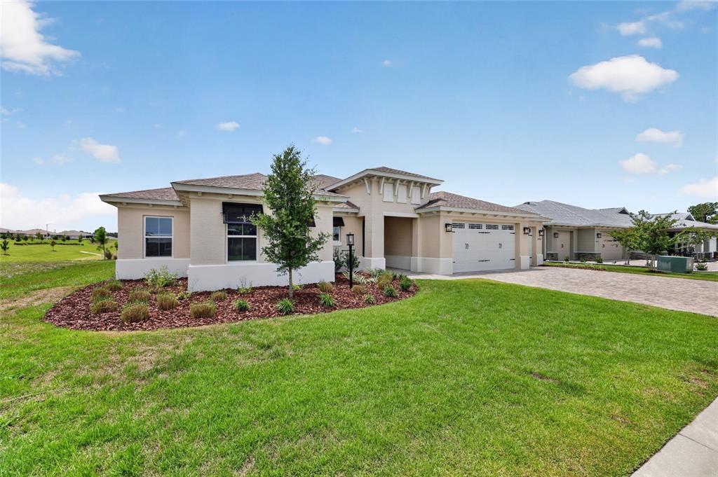 A single-story tan house with a paved driveway and a landscaped front yard — 10706 SW 99TH PLACE, OCALA, FL