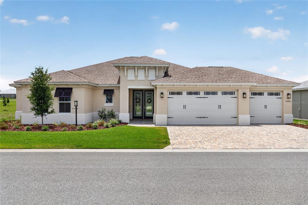A single-story house with a beige stucco exterior, a three-car garage, and a paved driveway — 10706 SW 99TH PLACE, OCALA, FL