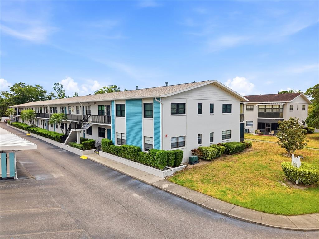 A two-story apartment building with blue siding and a parking area in the foreground — 5967 TERRACE PARK DRIVE N UNIT 201, ST PETERSBURG, FL