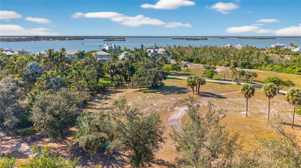 An aerial view shows a large, grassy vacant lot with scattered palm trees near water — 326 USEPPA ISLAND, CAPTIVA, FL