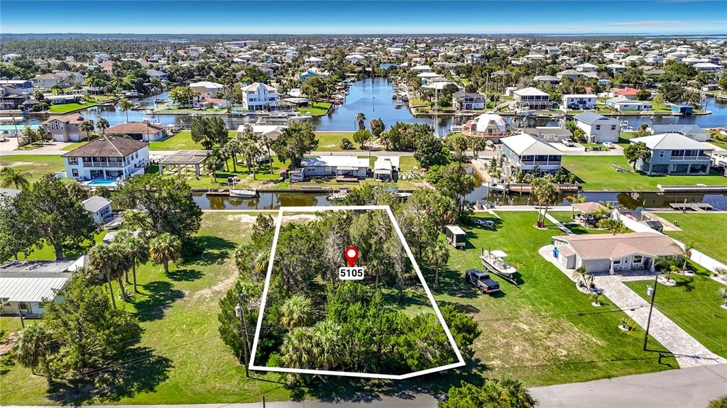 An aerial view shows a wooded, rectangular vacant lot outlined in white near a canal — 5099 CEDARBROOK LANE, HERNANDO BEACH, FL