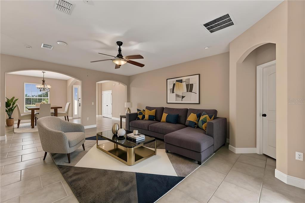 A living room with a gray sectional sofa, a glass coffee table, and tile flooring — 1451 DAYSTAR LANE, DELTONA, FL