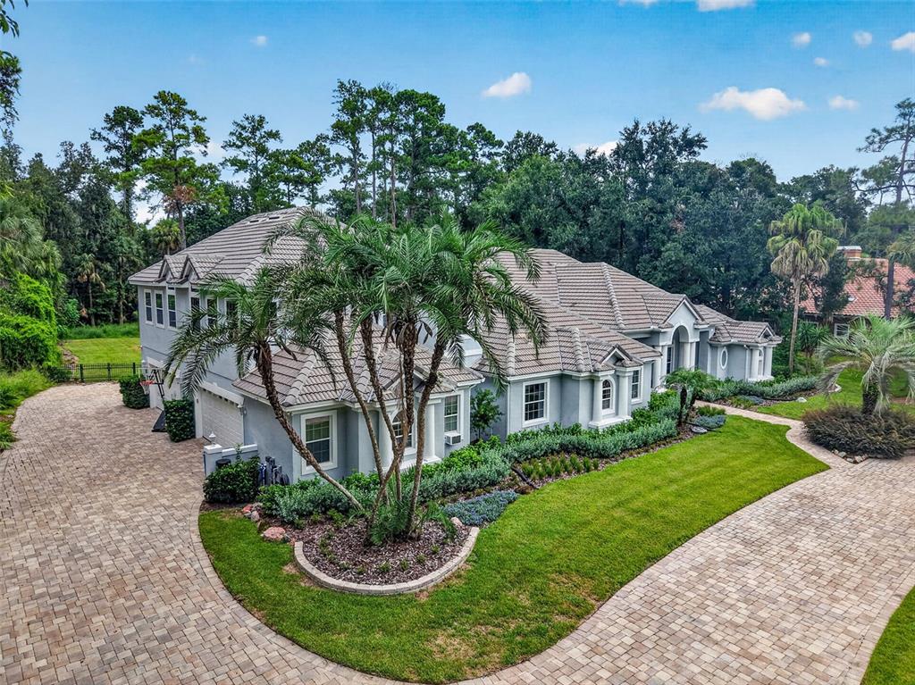 An aerial view of a large gray house with a tiled roof and paved driveway — 334 VISTA OAK DRIVE, LONGWOOD, FL