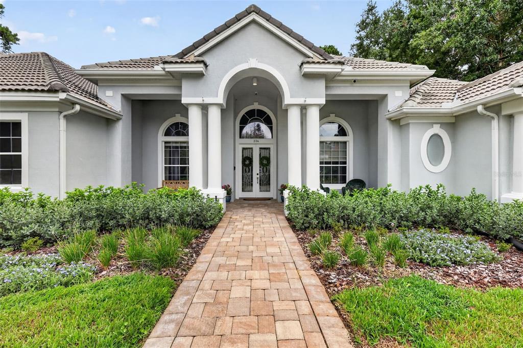A gray house with a stone walkway, arched entryway, and white columns — 334 VISTA OAK DRIVE, LONGWOOD, FL