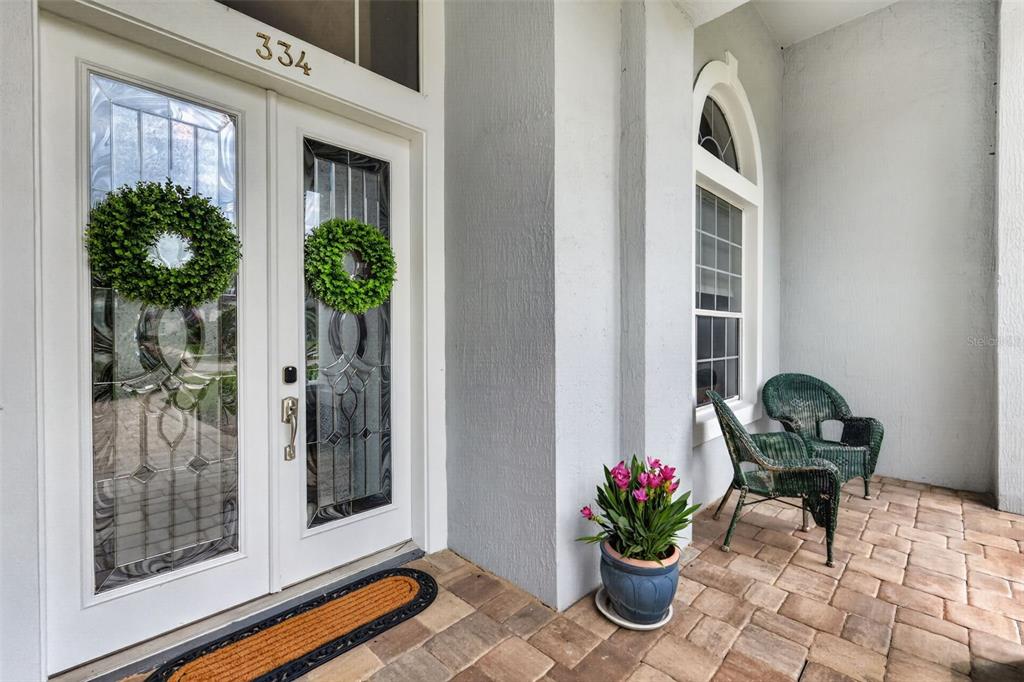 A front porch features double glass-paneled doors, two wicker chairs, and a potted plant — 334 VISTA OAK DRIVE, LONGWOOD, FL