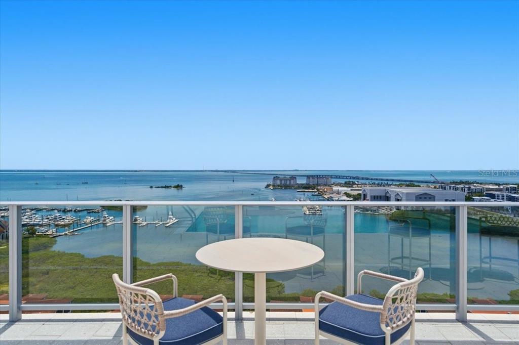 A balcony with a table and two chairs overlooks a marina and a large bay — 5713 BOWEN DANIEL DRIVE UNIT 1505, TAMPA, FL