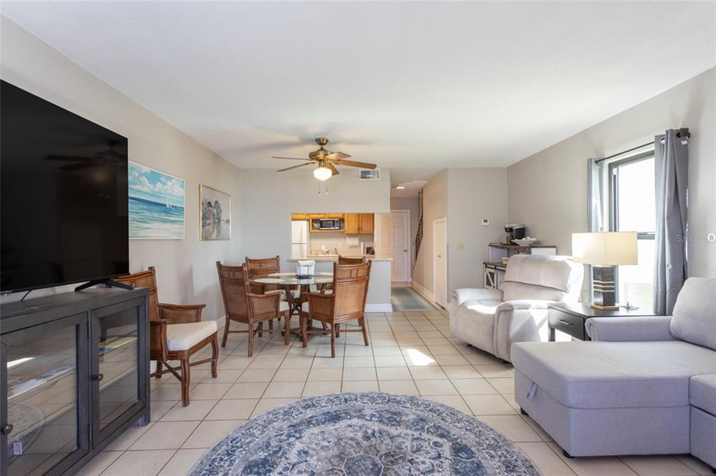 An open-concept living and dining area features tile flooring, a ceiling fan, and neutral walls — 10 OCEAN PALM VILLA N UNIT 10, FLAGLER BEACH, FL