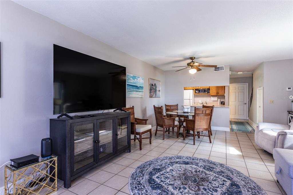 A living room with tile floors, a large television, and a dining area in the background — 10 OCEAN PALM VILLA N UNIT 10, FLAGLER BEACH, FL