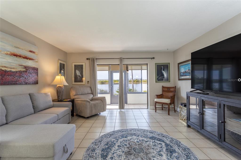 A living room features tile flooring, a sectional sofa, a recliner, and sliding glass doors — 10 OCEAN PALM VILLA N UNIT 10, FLAGLER BEACH, FL