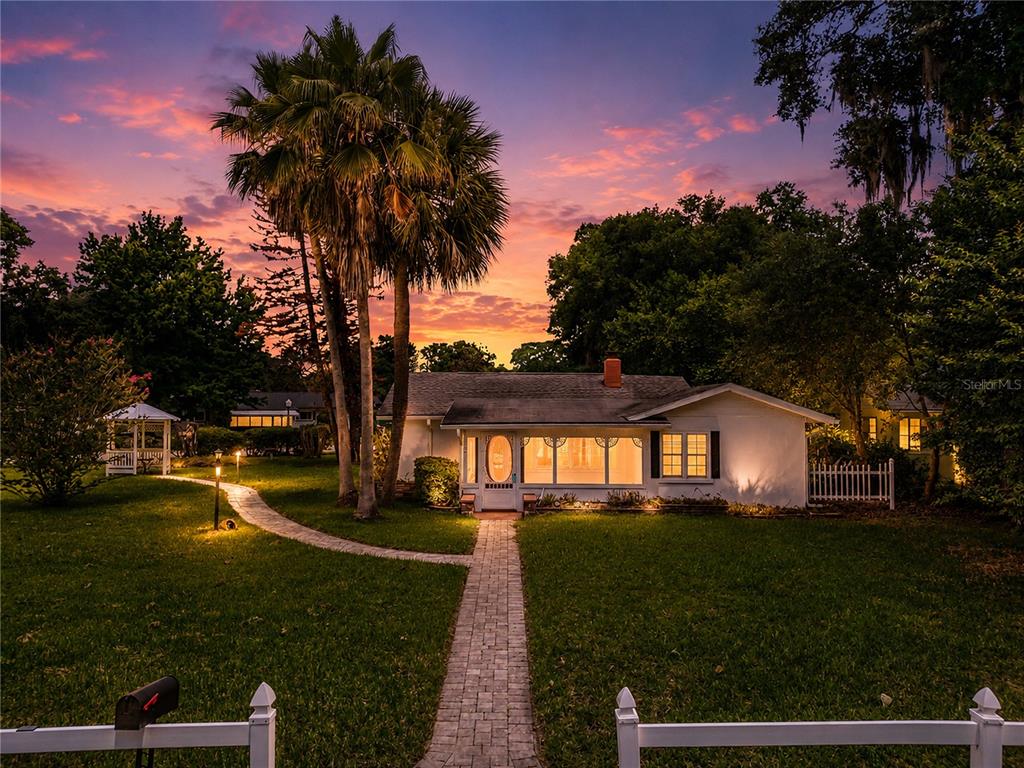 A white single-story house with a screened front porch sits behind a paved walkway — 1635 GERTRUDE PLACE, MOUNT DORA, FL
