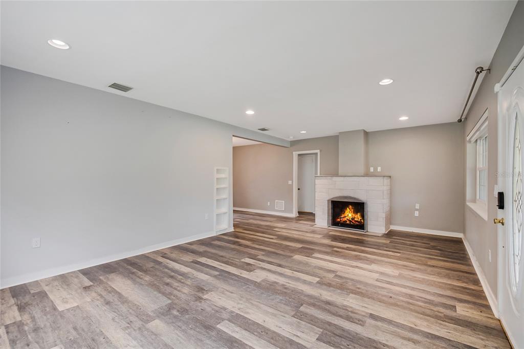 A living room features light gray walls, wood-look flooring, and a white stone fireplace — 1635 GERTRUDE PLACE, MOUNT DORA, FL