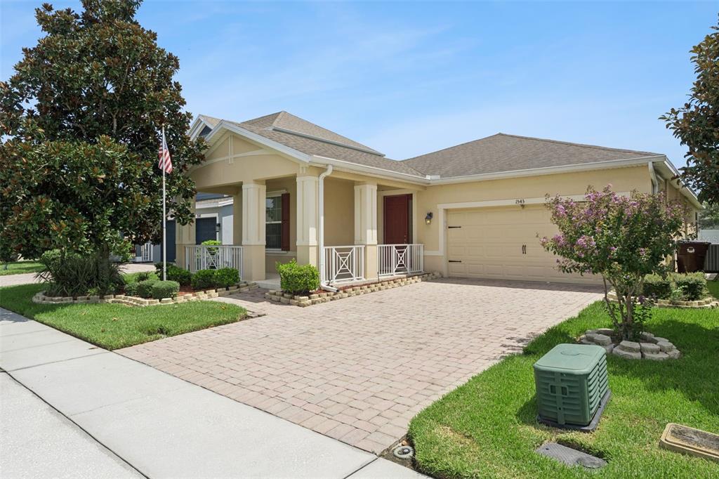 A single-story house with a beige stucco exterior, a paved driveway, and a front porch — 1543 CATERPILLAR STREET, ST CLOUD, FL