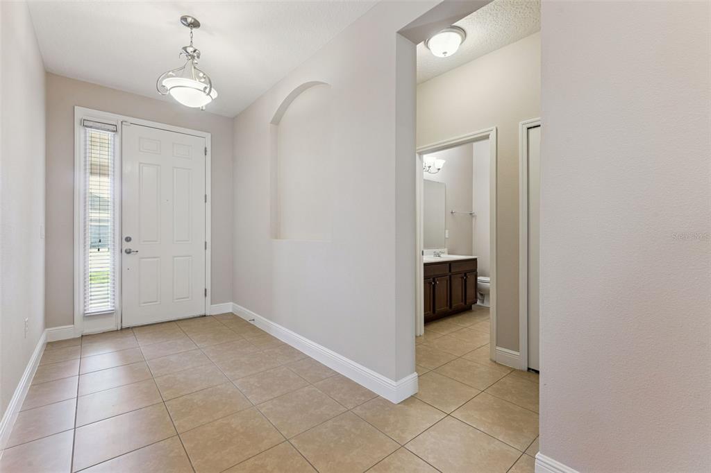 An entryway with tile flooring, a white front door, and an arched wall niche — 1543 CATERPILLAR STREET, ST CLOUD, FL