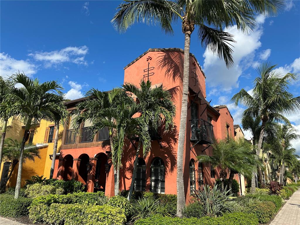 A multi-story orange stucco building with arched windows, balconies, and palm trees in front — 11220 PASEO GRANDE BOULEVARD UNIT 5204, FORT MYERS, FL