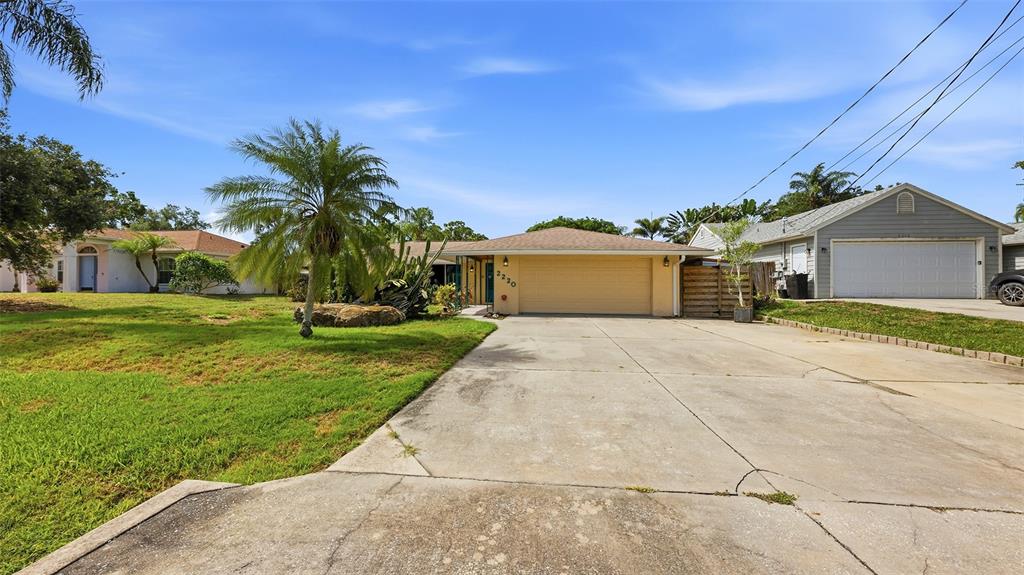 A single-story house with a beige exterior, a large driveway, and a detached garage — 2220 DOUD STREET, SARASOTA, FL