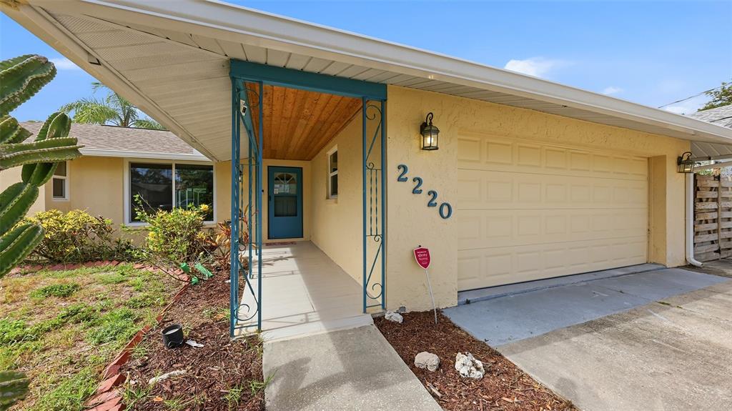A single-story house with a yellow stucco exterior, a blue front door, and a garage — 2220 DOUD STREET, SARASOTA, FL