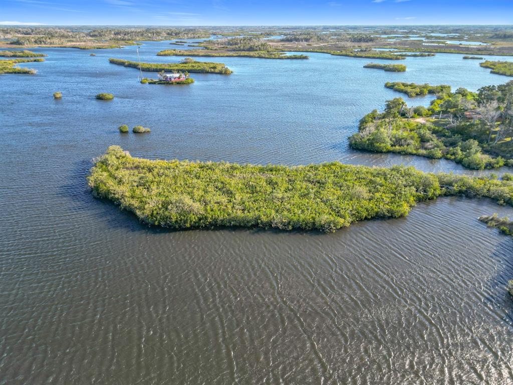 An aerial view shows a small house on a tiny island surrounded by marshy waterways — 14101 W ST MARTINS ROAD, CRYSTAL RIVER, FL