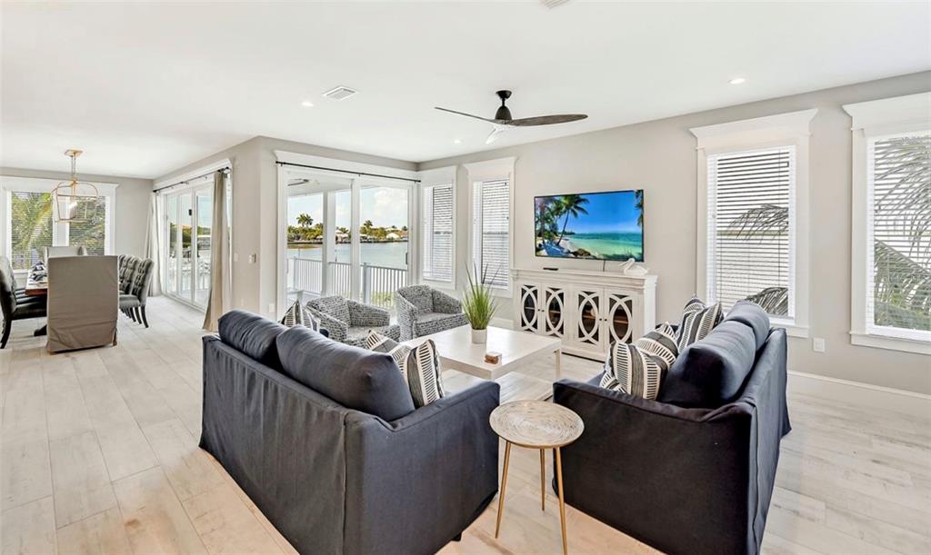 A bright living room features dark sofas, a white coffee table, and waterfront views — 2516 AVENUE A, BRADENTON BEACH, FL