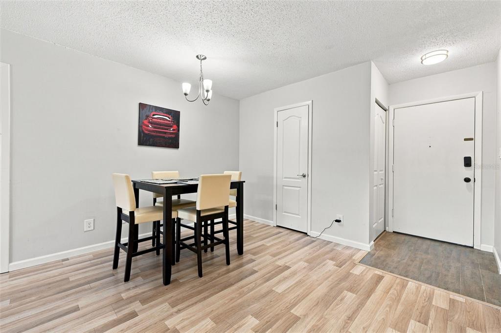 A dining area features a dark table with four chairs, light flooring, and a white door — 4606 W GRAY STREET UNIT 301, TAMPA, FL