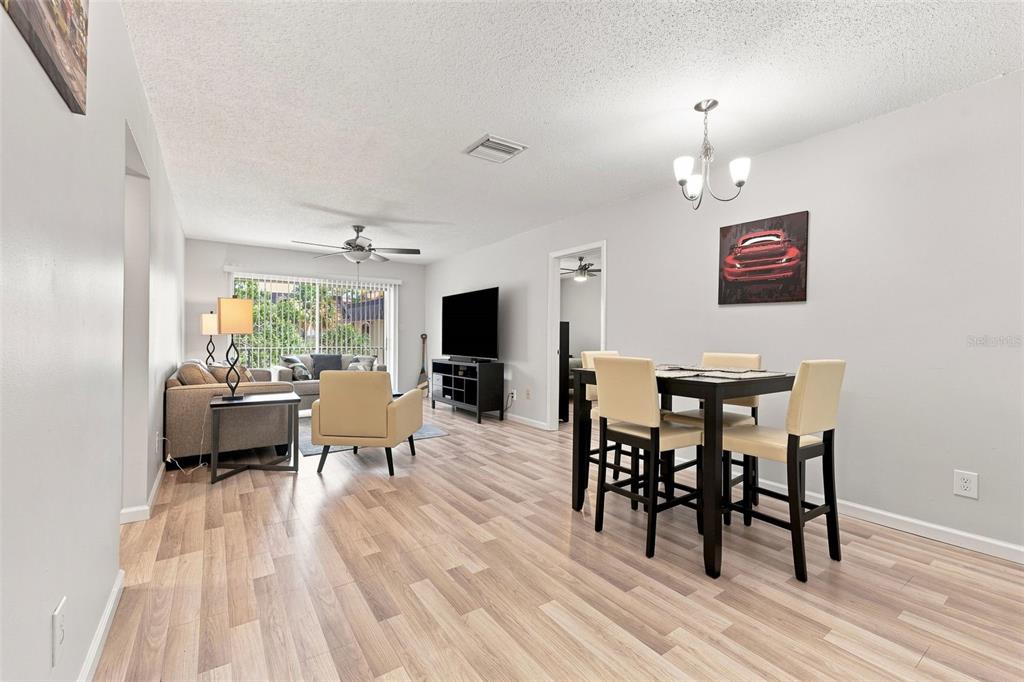 An open-concept living and dining area with light wood-look flooring and a ceiling fan — 4606 W GRAY STREET UNIT 301, TAMPA, FL