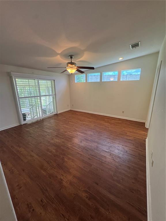 An open-concept living room features wood-look flooring, a ceiling fan, and a pass-through kitchen — 585 OUTER DRIVE, COCOA, FL