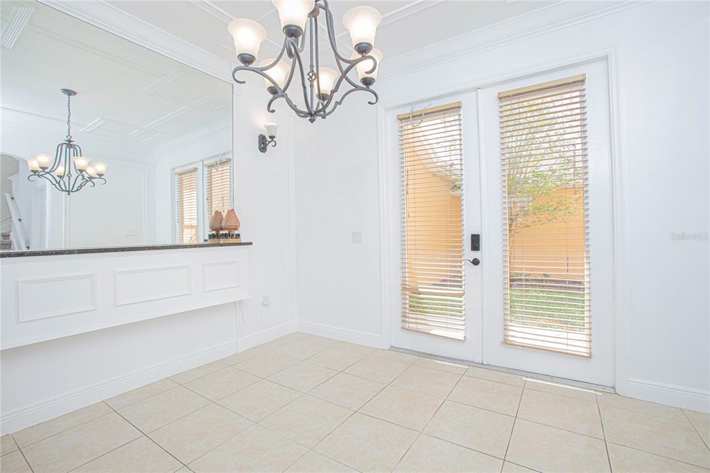 A dining area features a chandelier, a large mirror, tile flooring, and glass-paned double doors — 4908 TERRAPIN BOULEVARD, ST CLOUD, FL