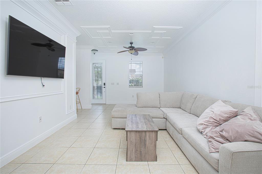 A living room features a large sectional sofa, a coffee table, and a wall-mounted television — 4908 TERRAPIN BOULEVARD, ST CLOUD, FL