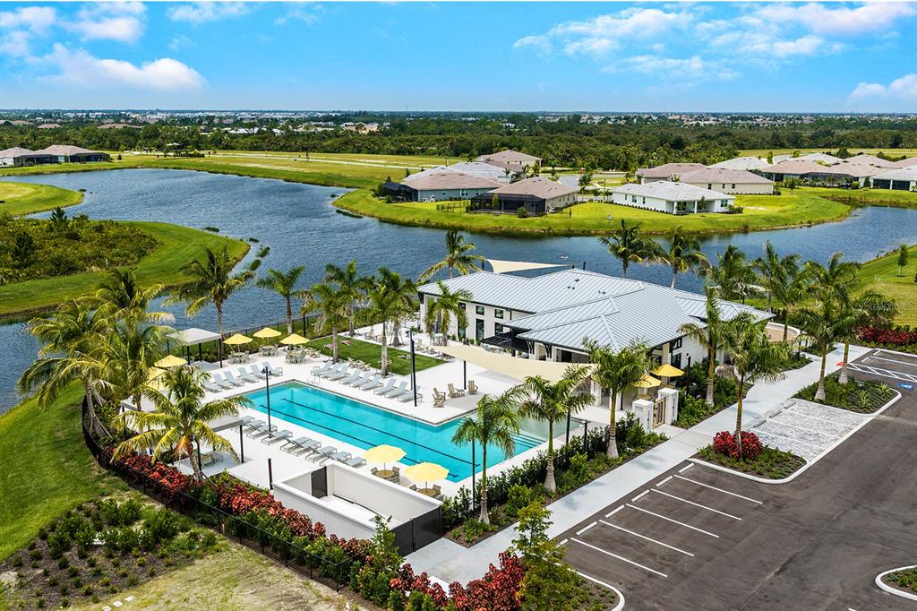 An aerial view of a clubhouse with a swimming pool, parking lot, and a pond — 12209 NEW TRANQUILITY PATH, VENICE, FL