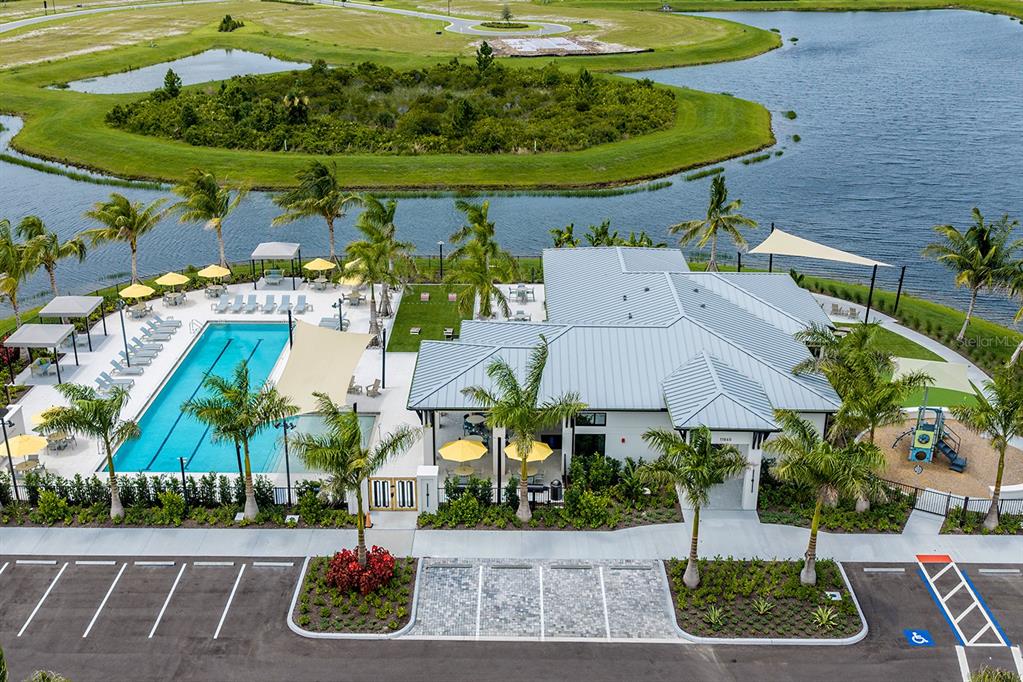 A modern house exterior features a metal roof, white walls, and a prominent entryway tower — 12209 NEW TRANQUILITY PATH, VENICE, FL