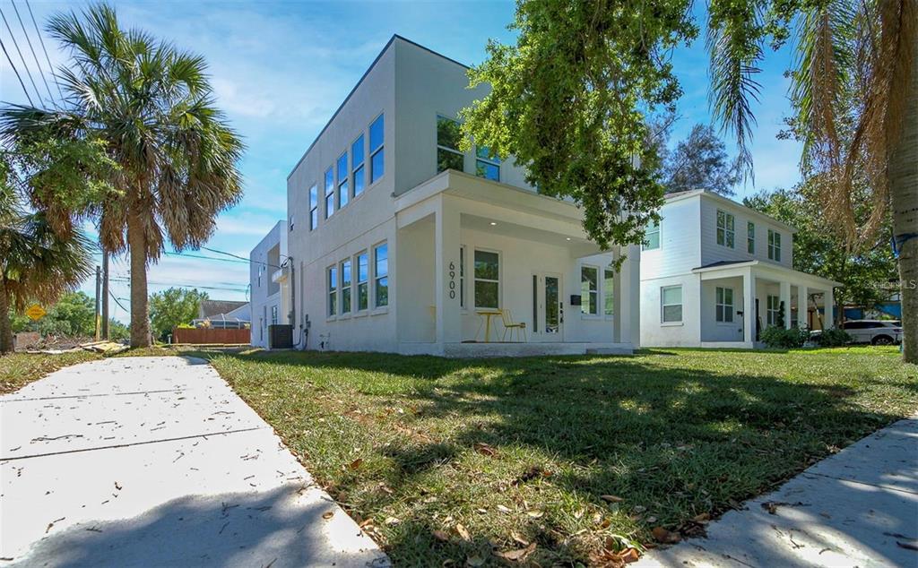 A white two-story house with a covered walkway connecting to an adjacent building — 6910 DARTMOUTH AVENUE N, ST PETERSBURG, FL