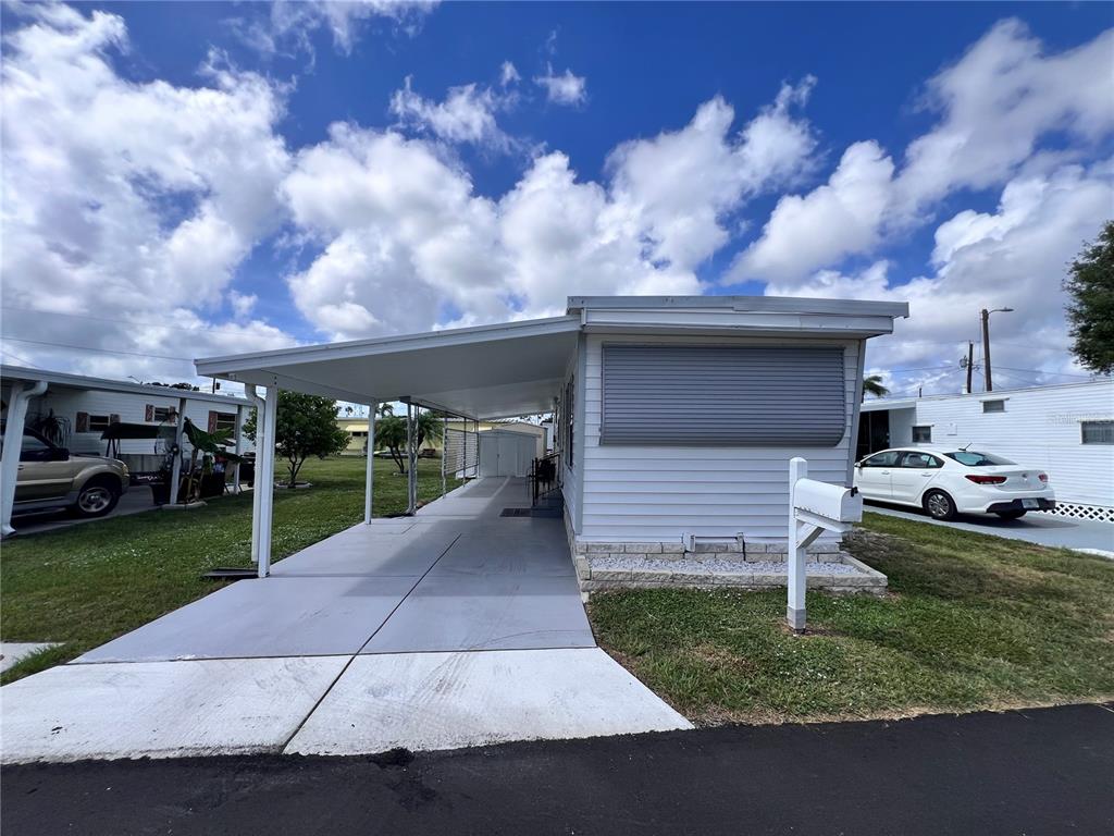A white mobile home features a covered carport and a gray metal storm shutter — 12674 SEMINOLE BOULEVARD UNIT C35, LARGO, FL