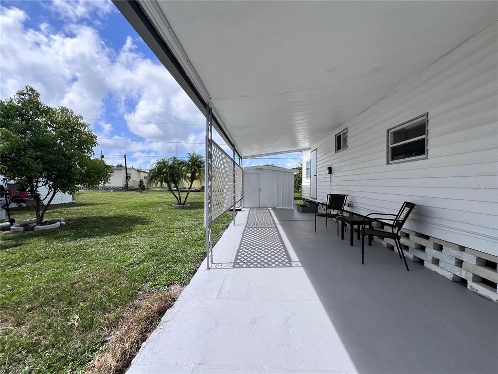 A covered concrete patio with a lattice privacy screen and two chairs beside a house — 12674 SEMINOLE BOULEVARD UNIT C35, LARGO, FL