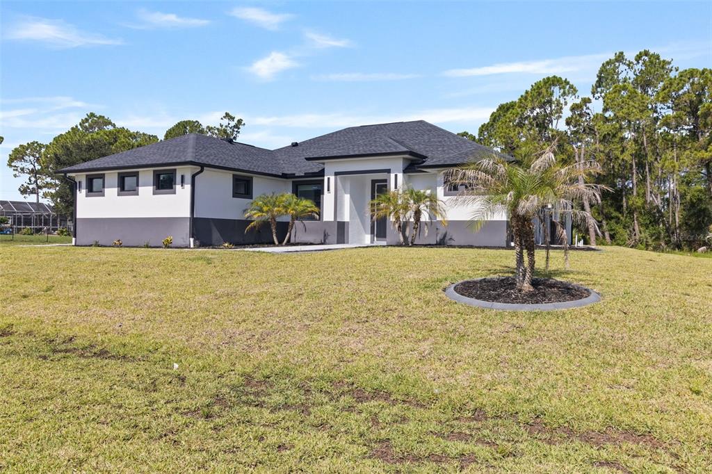 A modern single-story house with a white and gray exterior sits on a grassy lot — 2385 ECKER TERRACE, NORTH PORT, FL