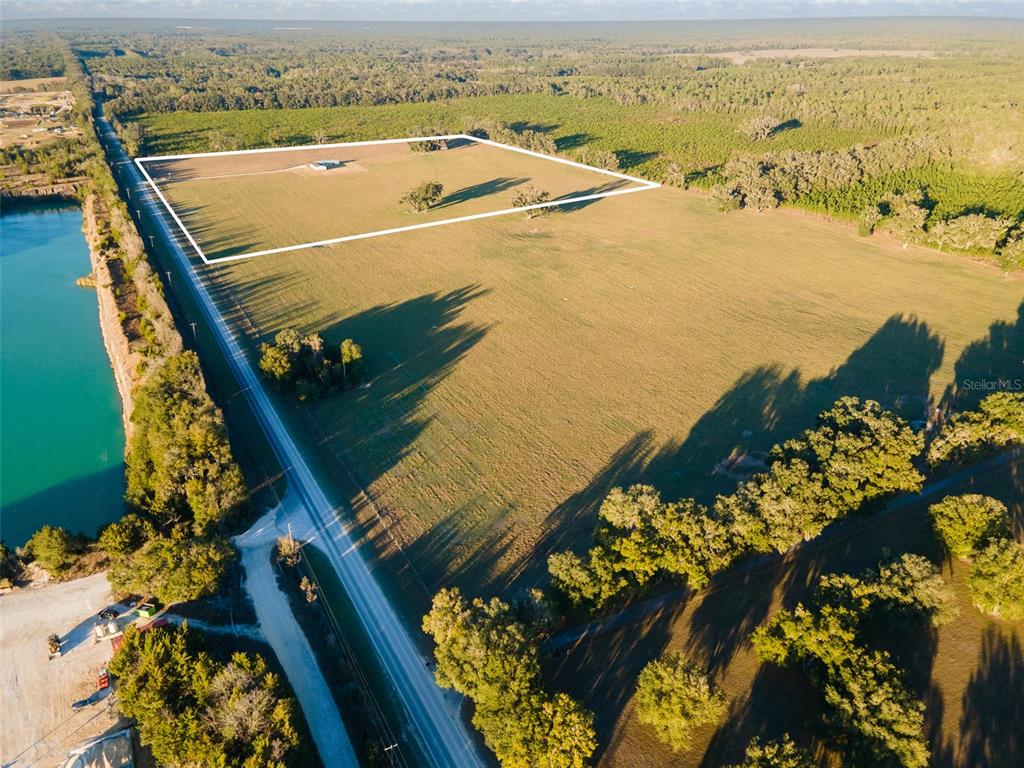 An aerial view shows a large, rectangular grassy field with a small building and trees — 3789 NW 202ND STREET, NEWBERRY, FL