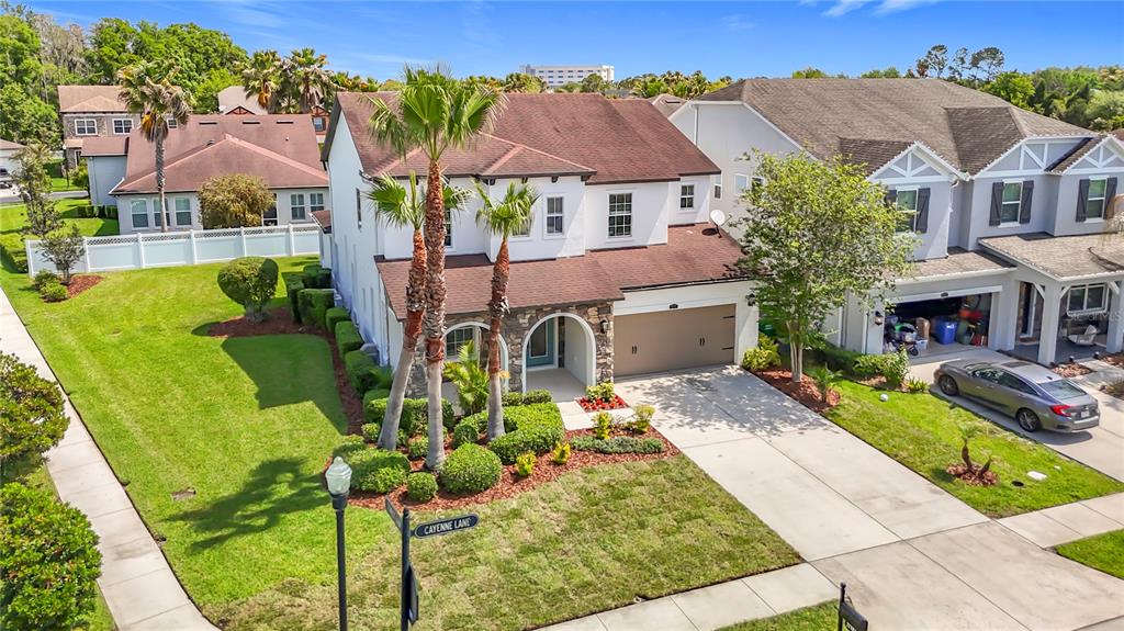 A two-story suburban house with a stone facade, a two-car garage, and palm trees — 27387 CAYENNE LANE, WESLEY CHAPEL, FL