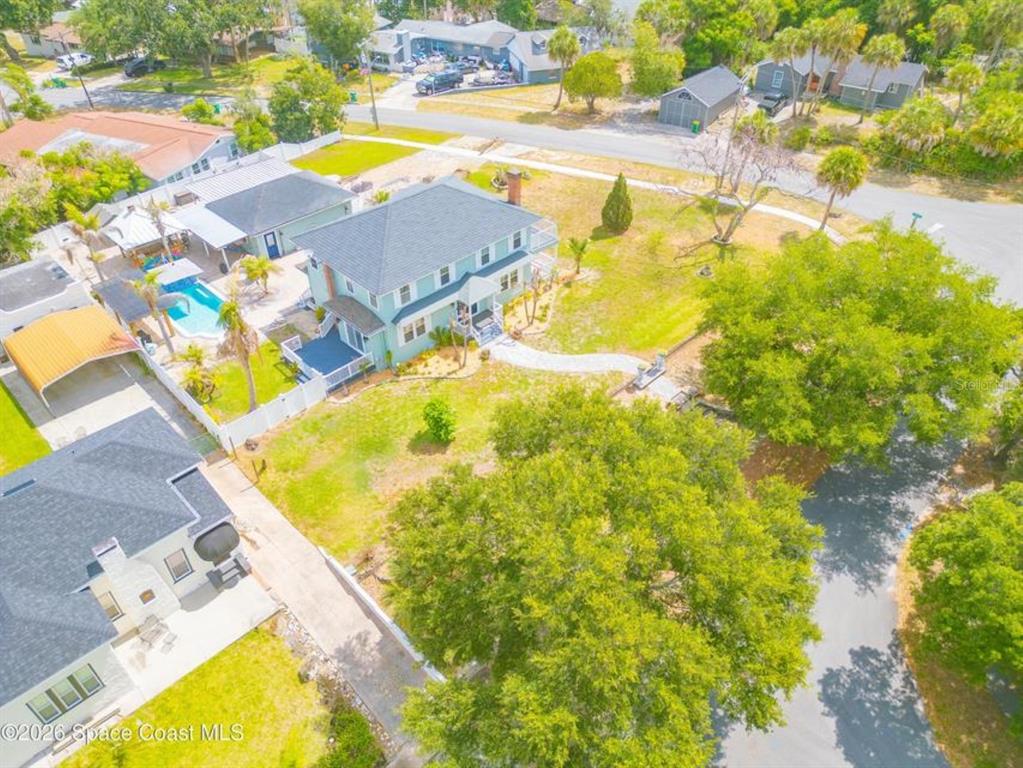 An aerial view shows a two-story house with a pool, patio, and surrounding trees — 308 BELLAIR DRIVE, COCOA, FL