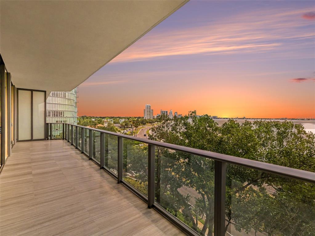 A balcony with a glass railing overlooks a city skyline and water at sunset — 3101 W BAYSHORE STREET UNIT 502, TAMPA, FL